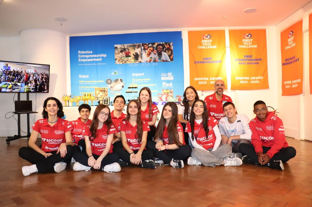 Equipe Amigos Droids, da DHEL, diante do mural de troféus e das faixas do FIRST Tech Challenge.
